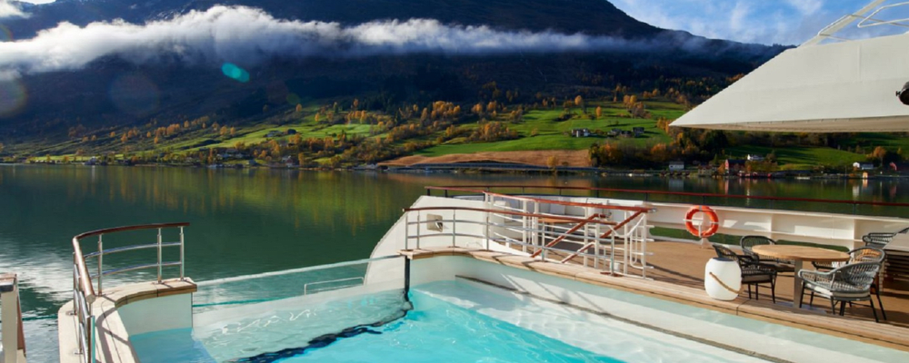 Pool deck with mountains in the background aboard the Ponant Le Chaplain