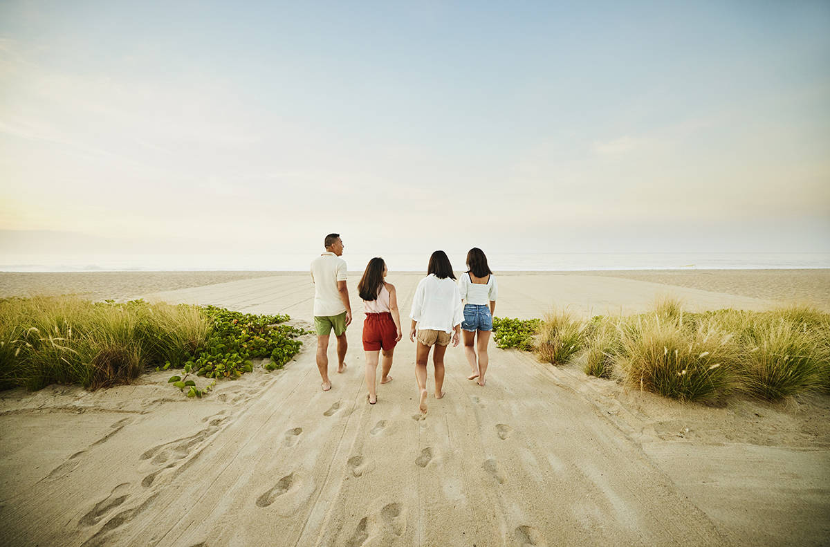 Wide shot of family walking onto beach at sunrise during vacation
